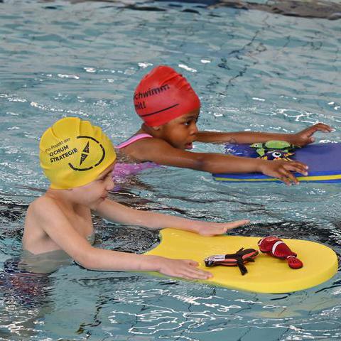 Zwei jungen, die mit Schwimmbrett im Wasser Schwimmen lernen.