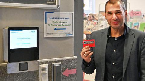 Meheddiz Bürle ist Leiter der Stadtbücherei. Er zeigt den Büchereiausweis in die Kamera. 
