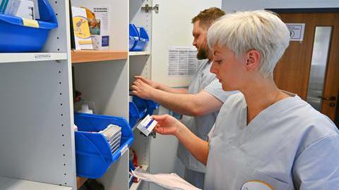 Zwei Pflegekräfte stehen vor einem Medikamentenschrank.