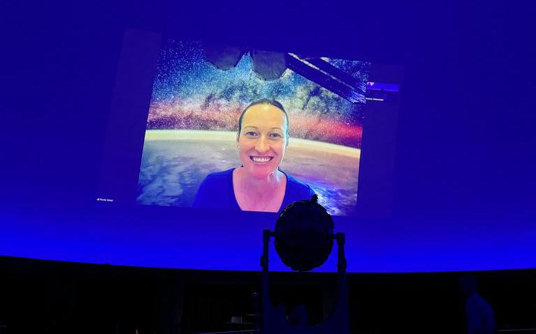 Das Bild zeigt Astronautin Nicola Berger über eine Videokonferenz zugeschaltet auf blauem Hintergrund.