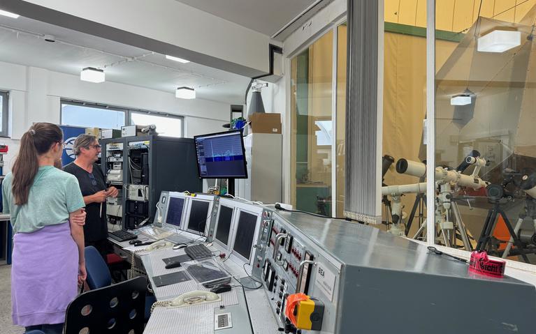 Ein Kontrollraum mit vielen Computern, rechts eine Glasscheibe, durch die die Personen in die Sternwarte blicken können.