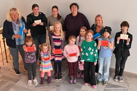 Gruppe von Kindern und Erwachsenen mit Gutscheinen in der Hand.
