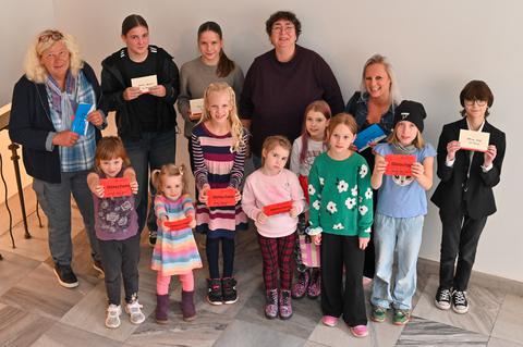Gruppe von Kindern und Erwachsenen mit Gutscheinen in der Hand.