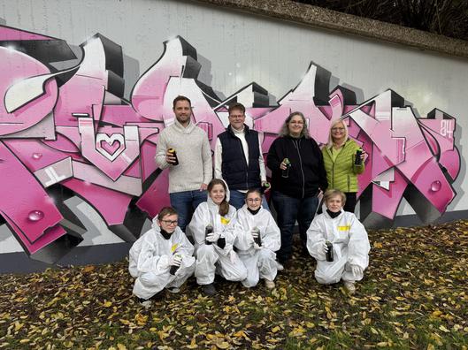 Gruppe von Erwachsenen und Kindern mit Graffitidosen in der Hand.