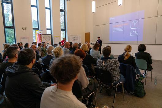 Eine Frau hält einen Vortrag vor einer Gruppe von Menschen.