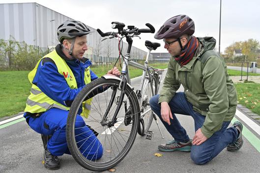 Zwei Personen knien neben einem Fahrrad.