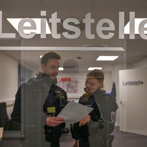 Zwei Mitarbeiter der Citywache stehen in Uniform hinter einer Glastür. 