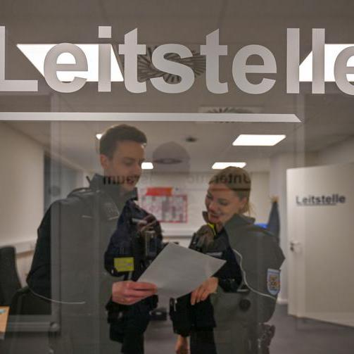 Zwei Mitarbeiter der Citywache stehen in Uniform hinter einer Glastür.