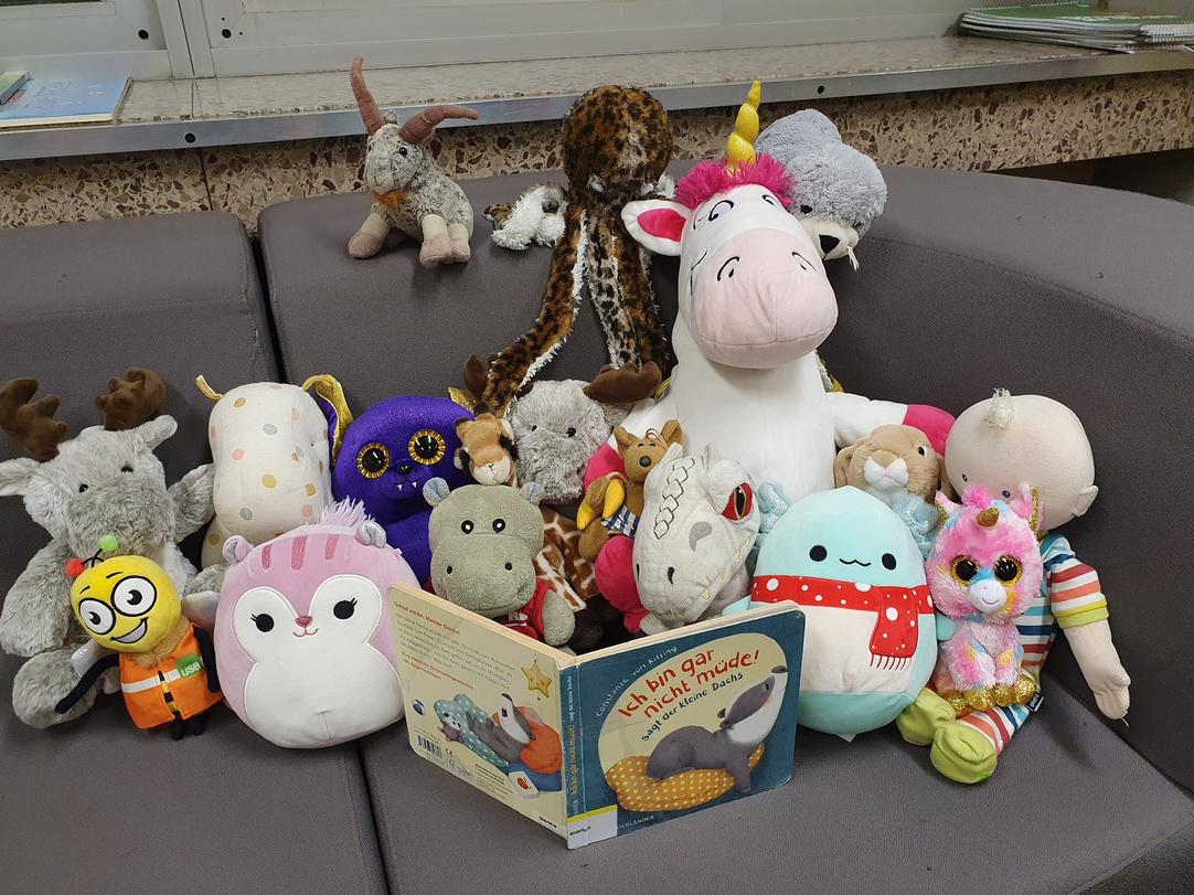 Kuscheltiere auf einer Couch mit einem Buch