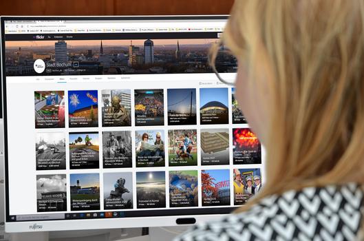 Eine Frau schaut sich den Flickr-Account der Stadt Bochum auf ihrem PC an.