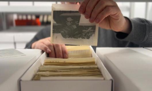 Ein Mann holt historische Bilder aus einem Karton.