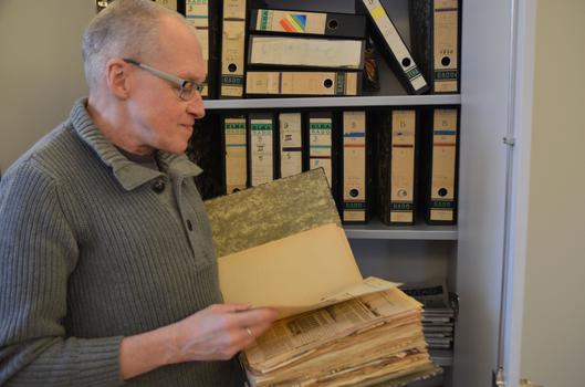 Ein Mann blättert durch historische Presseartikel in einem Ordner.