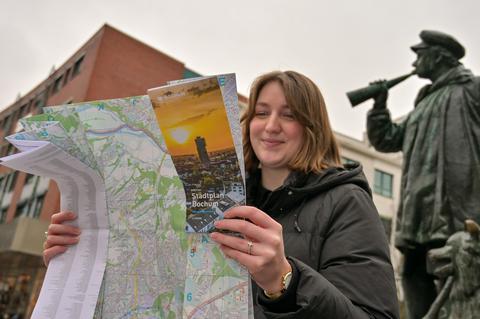 Der neue amtliche Stadtplan wird vor dem Kuhhirten-Denkmal von einer Frau betrachtet