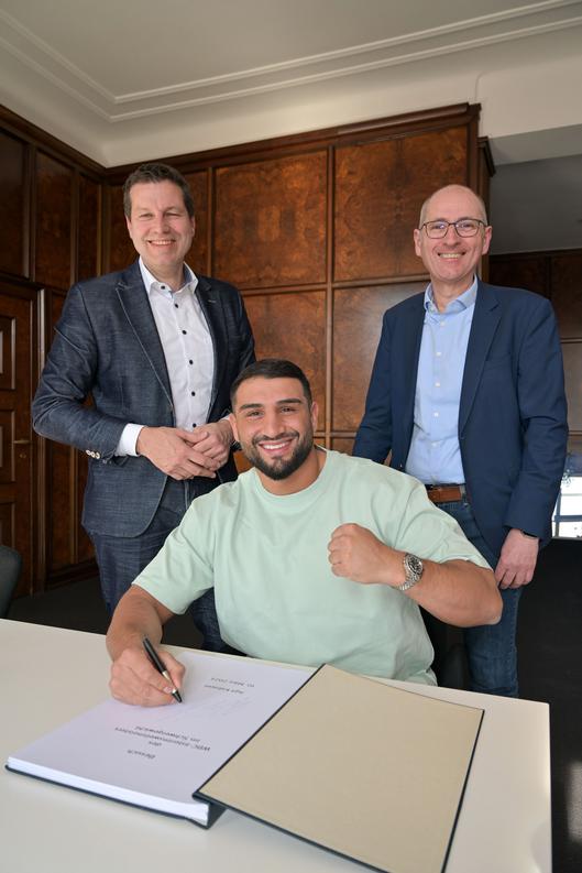 Boxer Agit Kabayel besucht Oberbürgermeister Thomas Eiskirch sowie Sportdezernent Dietmar Dieckmann und trägt sich in das Gästebuch der Stadt Bochum ein.