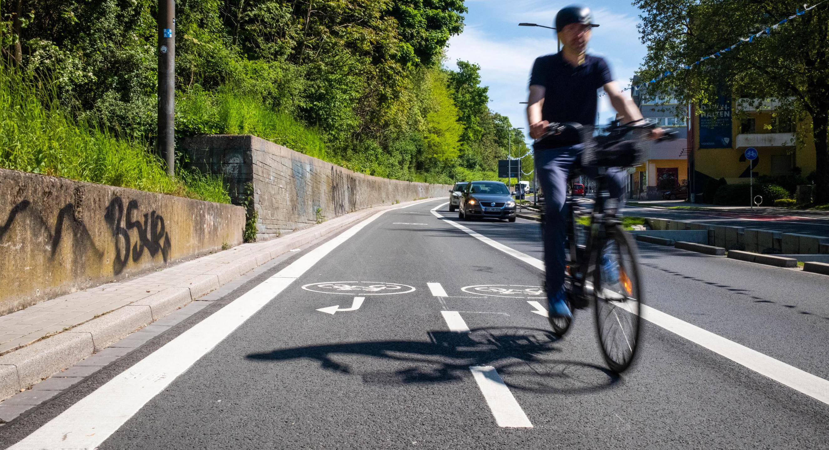 Ein Mann auf einem Fahrrad auf einem neuen Fahrradweg an einer Straße.
