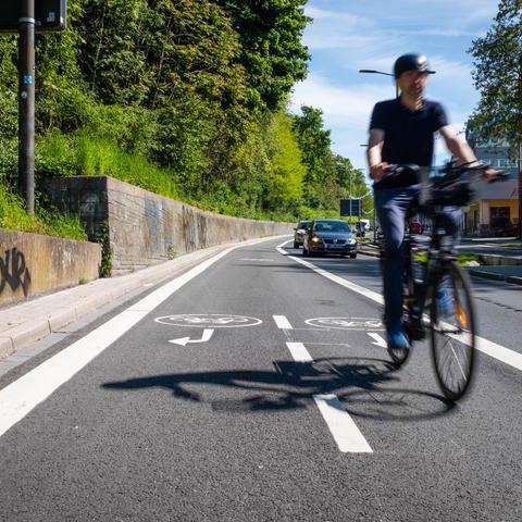 Ein Mann auf einem Fahrrad auf einem neuen Fahrradweg an einer Straße. 