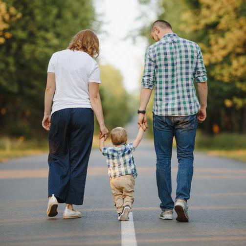 Eltern laufen mit dem Kind an der Hand eine Straße entlang.
