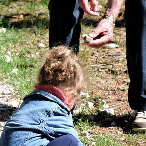 Ein Mann reicht einem Kind einen Stein.