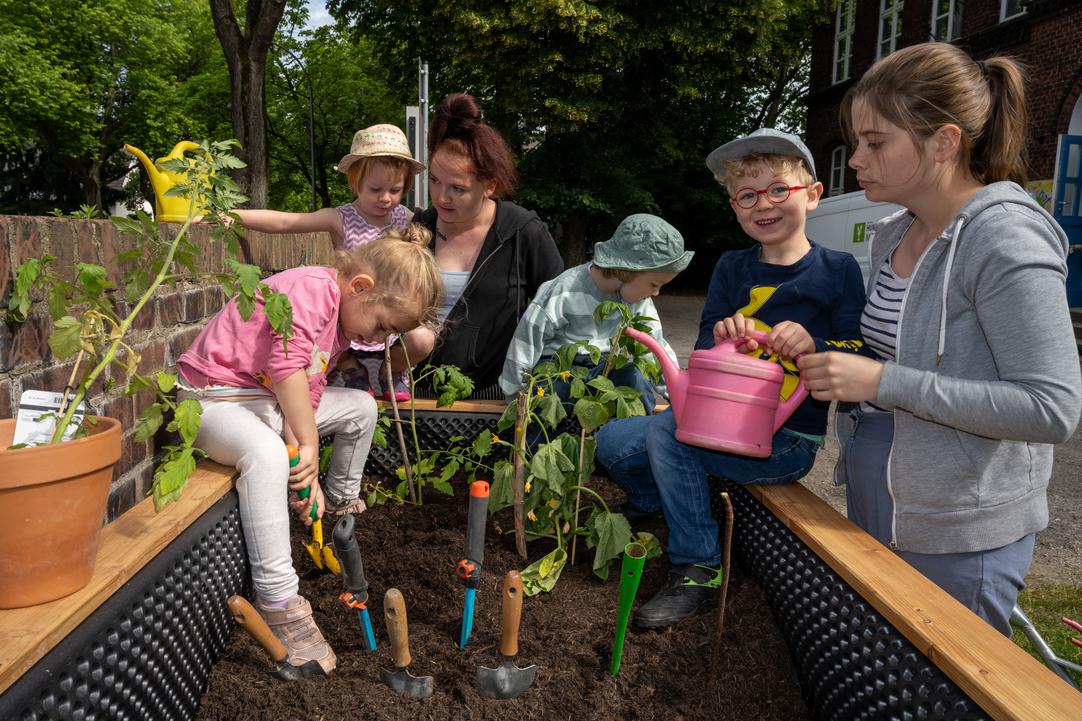 Kinder des „Kinderhofs Bochum“ bei der Bepflanzung ihres Hochbeets mit Himbeeren und Tomaten