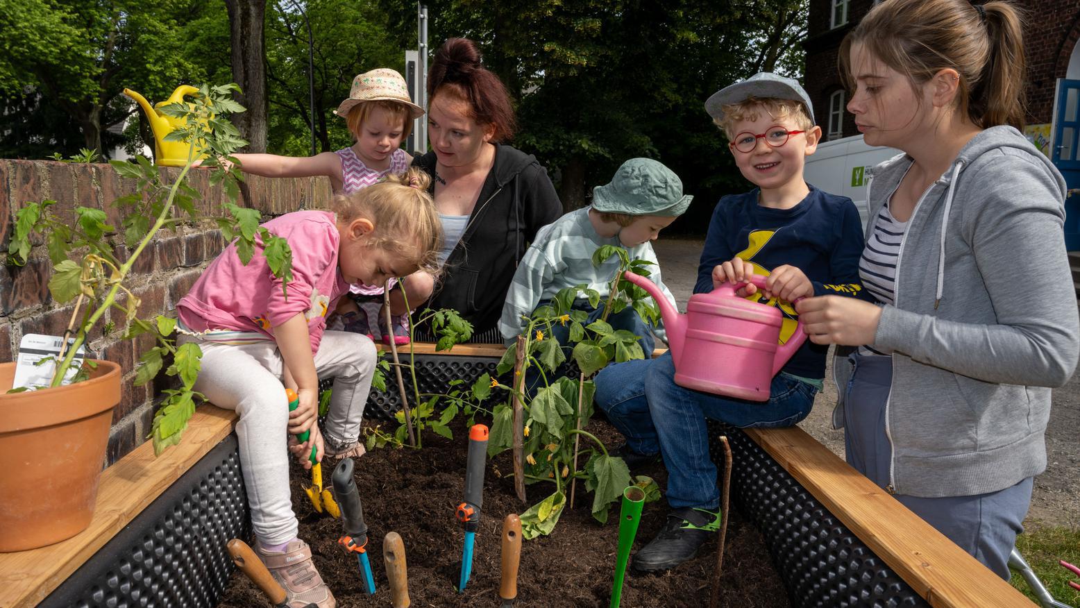 Kinder des „Kinderhofs Bochum“ bei der Bepflanzung ihres Hochbeets mit Himbeeren und Tomaten