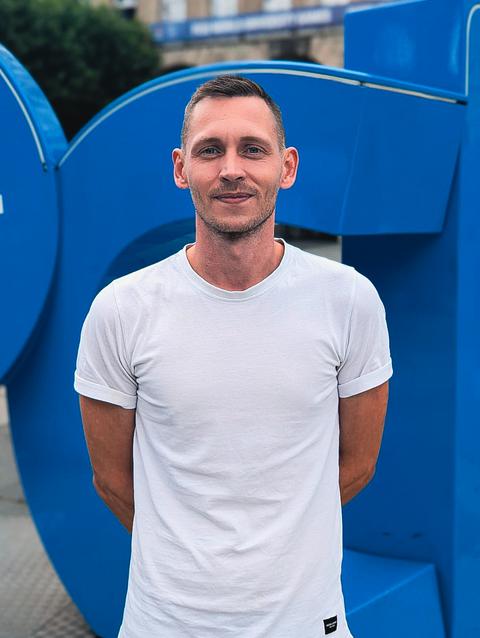 Ein Porträtfoto von Thomas vor dem bochum-Logo.
