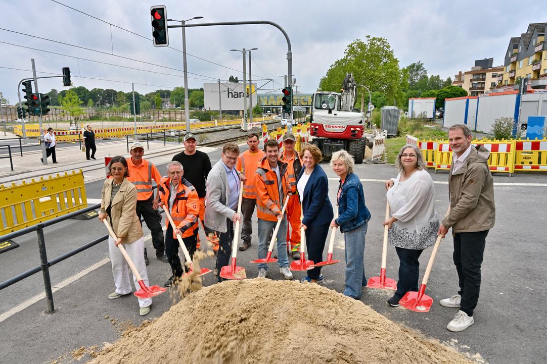Eine Personengruppe macht den ersten Spatenstich vor der Baustelle an der Wittener Straße.