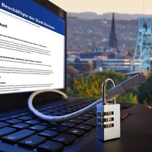 Ein Laptop ist mit einem Schloss gesichert. Im Hintergrund sieht man Bochum.