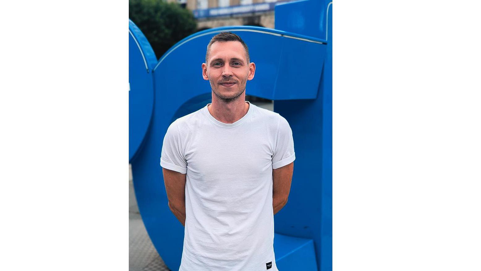 Ein Porträtfoto von Thomas vor dem Bochum-Logo.