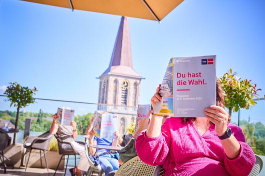 Mehrere Personen lesen das neue Programmheft der Volkshochschule der Stadt Bochum.