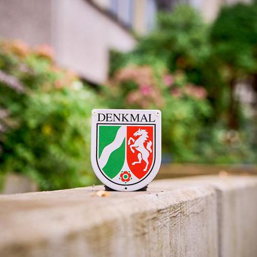 Denkmalplakette mit dem Terrassenhaus an der Schattbachstraße im Hintergrund