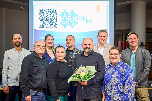 Der neue Bochumer Jugendamtselternbeirat 2025/2026 (namentlich von vorne links): Fabian Wagner, Magdalena Zomerfeld, Stefan Uhlmann (Vorsitzender, mit Blumen), Agnes Hannig, Dahinter: Daniele Giustulisi, Jennifer Affeld, Tassilo Pütter, Jens Vieting (Sozialdezernent) und Christian Papies (Jugendamtsleiter) 