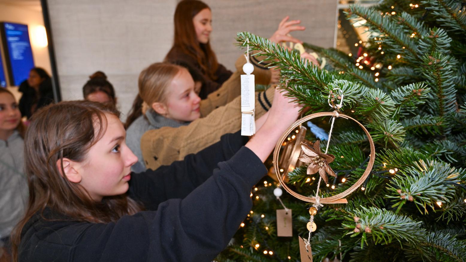 Kind hängt Schmuck an Weihnachtsbaum