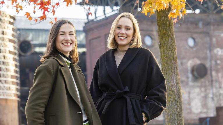 Zwei junge Frauen stehen im Herbstwetter vor der Jahrhunderthalle in Bochum.