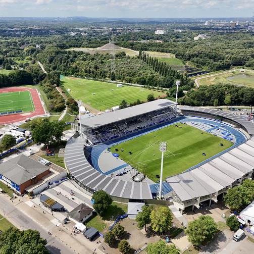 Luftaufnahme des Lohrheidestadions mit blauer Tartanbahn, Tribünen und umliegenden Grünflächen.