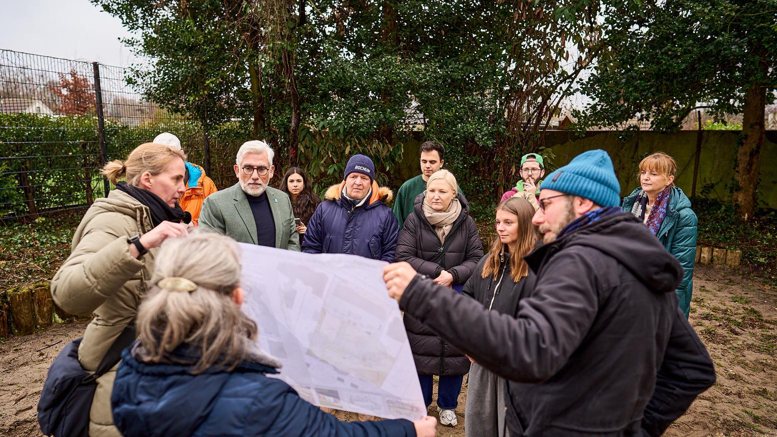 Die Gruppe schaut sich gemeinsam den Bauplan der Umgestaltung an. 