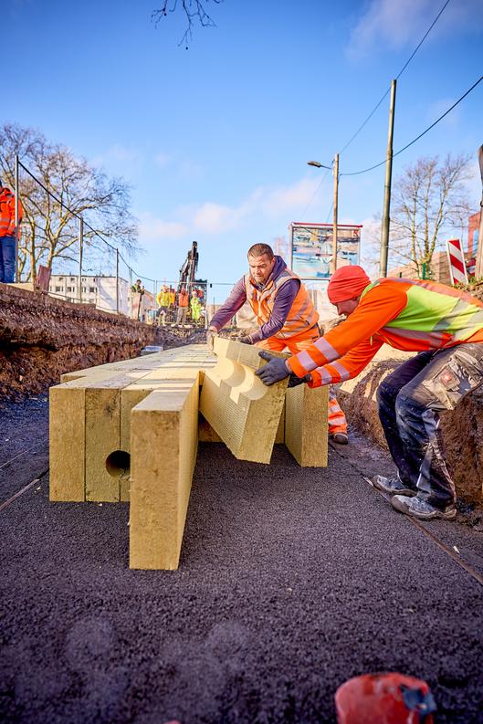 Die Bauarbeiter setzen die Steinwolle in die Grube 