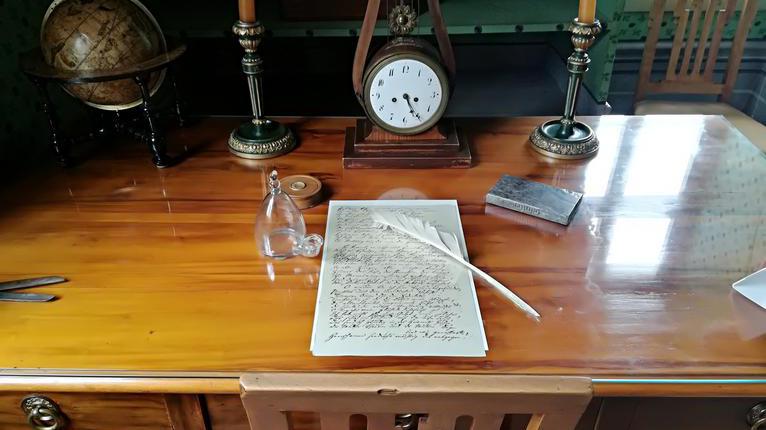 Historischer Schreibtisch mit Federkiel und Manuskript.