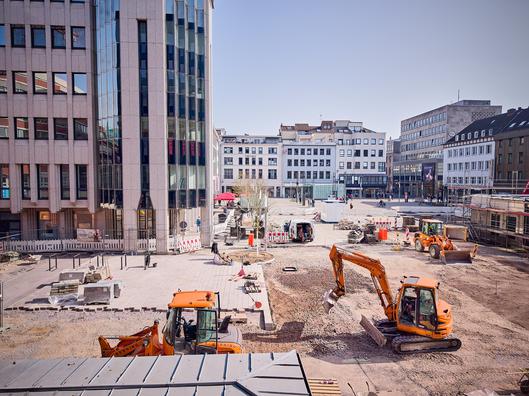 Blick auf die Baustelle am Husemannplatz: Aktuelle Pflaster- und Erdarbeiten zur Neugestaltung der zentralen Platzfläche.