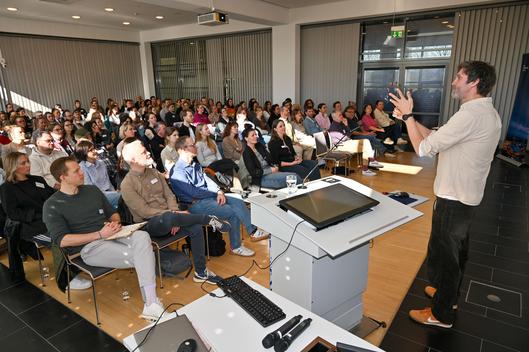 Ein Referent präsentiert Ergebnisse vor rund 140 Teilnehmenden der Bochumer Jugendhilfe.