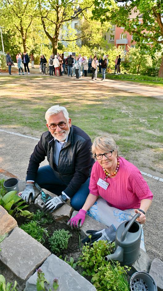 Oberbürgermeister Lukat und eine Frau bepflanzen Beete.