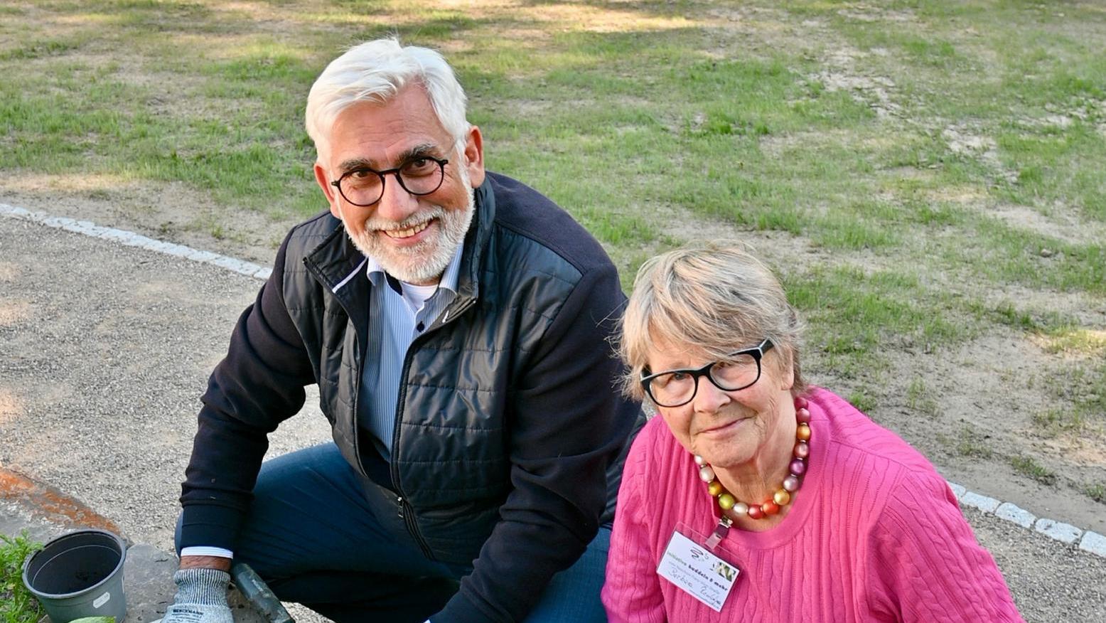 Oberbürgermeister Lukat und eine Frau bepflanzen Beete.