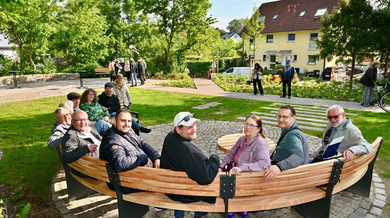 Bürgerinnen und Bürger sitzen auf einer Rundbank
