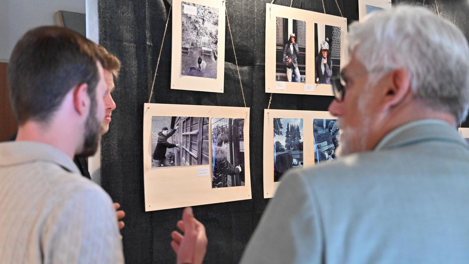 Oberbürgermeister Jörg Lukat betrachtet gemeinsam mit einem Besucher die Fotografien einer Ausstellung.