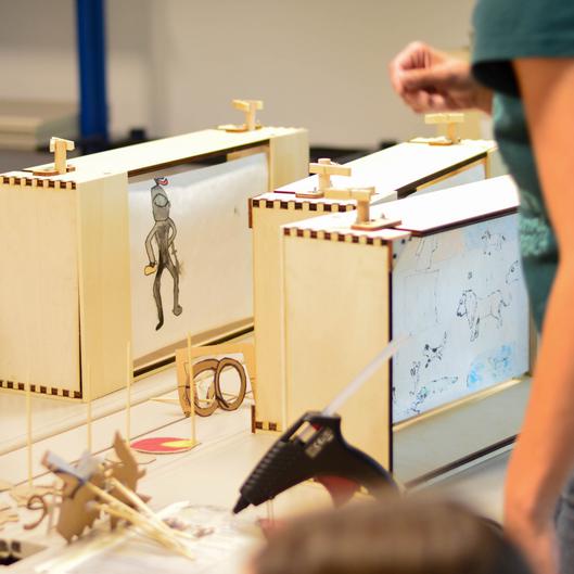 Selbstgebaute Animationskästen mit gezeichneten Figuren bei einem kreativen Workshop.