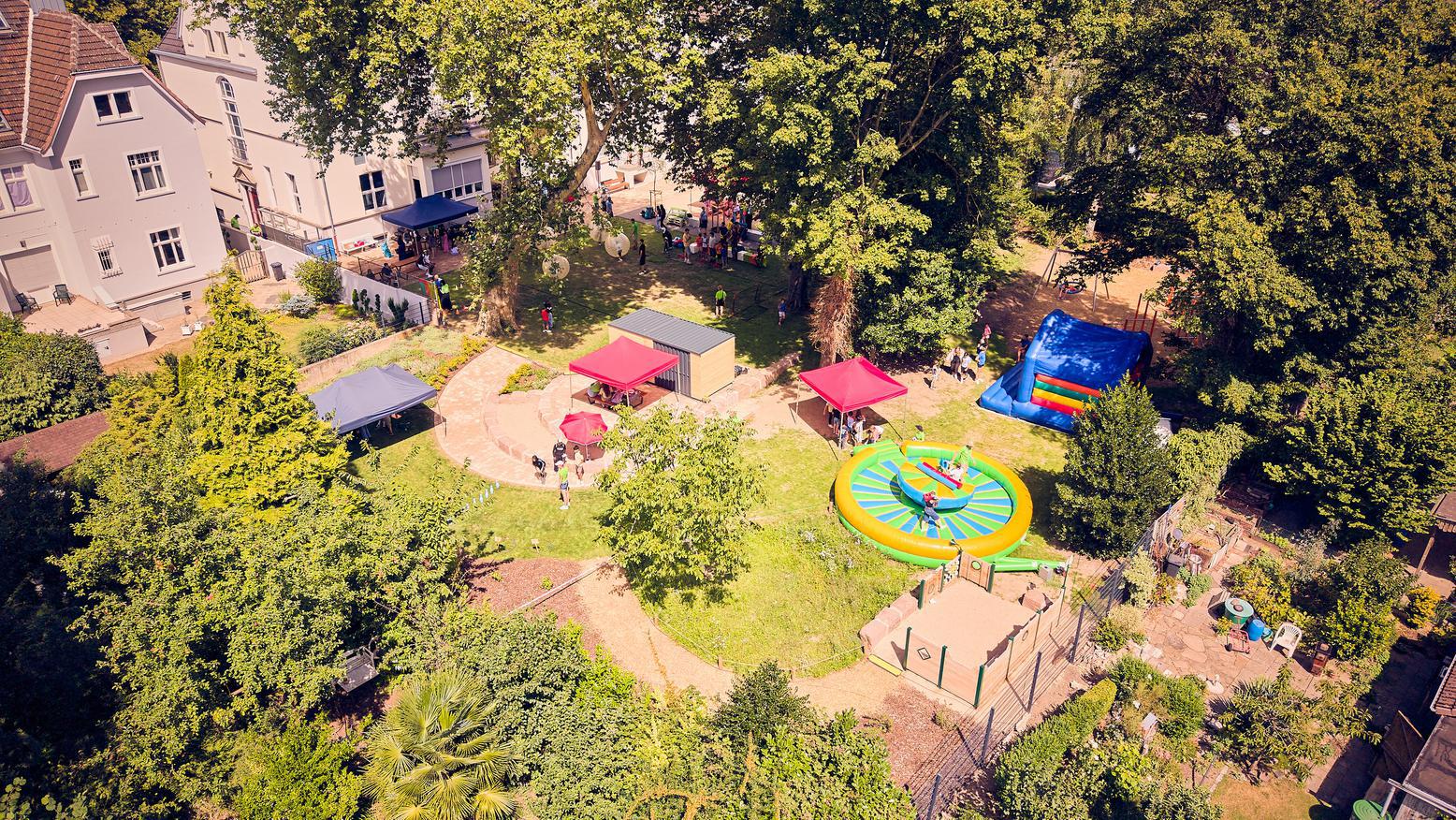 Luftaufnahme des Außengeländes mit Spiel- und Freizeitangeboten, Pavillons und zahlreichen Besucherinnen und Besuchern.