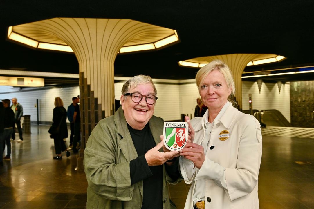 Zwei Personen halten die Denkmalplakette hoch
